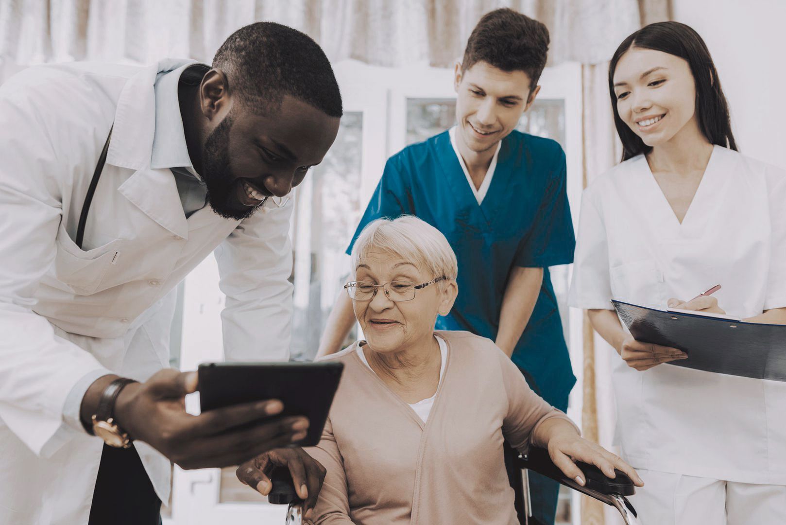 Ältere Dame im Rollstuhl wird von einem Arzt und Pflegedienst betreut